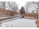 Snow covered outdoor deck area with built-in bench and grill in backyard with brick fence at 12107 E Vassar Dr, Aurora, CO 80014