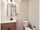 Cozy bathroom featuring vanity with wood cabinet, a mirror and toilet in a neutral color palette at 15224 W 73Rd Ave, Arvada, CO 80007