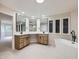Bright bathroom featuring a modern tub, double sink, large mirrors, and sleek fixtures at 15224 W 73Rd Ave, Arvada, CO 80007