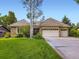 Well-maintained brick home with a three-car garage and a large, green lawn at 15224 W 73Rd Ave, Arvada, CO 80007