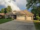 Single-story brick home featuring a three-car garage, complemented by a green lawn at 15224 W 73Rd Ave, Arvada, CO 80007