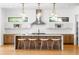 Modern kitchen boasts a large island with seating, designer lighting, stainless steel appliances, and bright white backsplash at 1241 S Garfield St, Denver, CO 80210