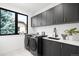 Well-lit laundry room featuring modern washer/dryer units, dark cabinetry, and a sleek sink area at 1241 S Garfield St, Denver, CO 80210