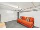 Finished basement featuring neutral carpet, painted ceiling, and an orange couch with decorative pillows at 4196 S Pennsylvania St, Englewood, CO 80113