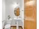 Bright powder room featuring a pedestal sink, oval mirror, and wood-look flooring, offering a functional and stylish space at 1100 Columbine Way, Erie, CO 80516