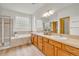 The luxurious bathroom offers dual sinks, wooden cabinets, a glass enclosed shower, and large soaking tub at 1100 Columbine Way, Erie, CO 80516