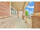 Charming covered porch with wood and brick accents, offering a cozy outdoor space to relax and enjoy neighborhood views at 1100 Columbine Way, Erie, CO 80516