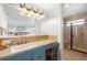 Bathroom featuring custom blue cabinets, tile floors, multiple lights, and a glass shower at 9151 E Harvard Ave, Denver, CO 80231