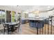 Elegant eat-in kitchen with a blue island, pendant lighting, white cabinetry, and access to the covered patio at 9151 E Harvard Ave, Denver, CO 80231