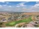 An aerial view displays a golf course community with lush fairways, well-manicured lawns, and stunning mountain views at 1199 Links Ct, Erie, CO 80516