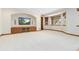 Carpeted basement area with a TV, built-in shelves, and natural light from the window at 1199 Links Ct, Erie, CO 80516