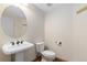 Powder room featuring a round mirror, a pedestal sink, and toilet at 1199 Links Ct, Erie, CO 80516