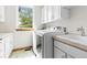 Well-lit laundry room with white cabinets, a sink, and modern washer and dryer appliances beneath a window at 1199 Links Ct, Erie, CO 80516