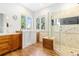 Bright bathroom with a walk-in shower, soaking tub and wood cabinets at 1199 Links Ct, Erie, CO 80516