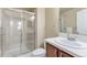 Bright bathroom featuring a shower with sliding doors, white tile, and a sink with dark wood cabinets at 7887 Vallagio Ln, Englewood, CO 80112