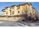 Multi-level townhome shows attached garage and neutral stucco exterior with stone accents at 7887 Vallagio Ln, Englewood, CO 80112