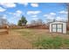 Fenced backyard with a shed, sparse grass, and a small deck off the house at 1436 S Yates St, Denver, CO 80219