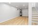 Unfinished basement area with light wood-look floors and stairs leading to the upper level at 1436 S Yates St, Denver, CO 80219