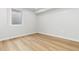 Basement area features an egress window, light wood-look flooring, and white trim at 1436 S Yates St, Denver, CO 80219