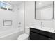Modern bathroom features white-tiled walls, a toilet, sink with a mirror, and updated fixtures at 1436 S Yates St, Denver, CO 80219