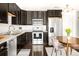 Bright kitchen with dark wood cabinetry, stainless steel appliances, hardwood floors, and eat-in dining area at 5025 Central Park Blvd, Denver, CO 80238