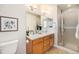 Well-lit bathroom with double sinks, wood cabinets, a large mirror and a glass enclosed shower at 8381 E 29Th Ave, Denver, CO 80238
