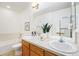 Well-lit bathroom featuring double sinks, wood cabinets, large mirror, and combined tub and shower at 8381 E 29Th Ave, Denver, CO 80238