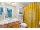 Bright bathroom with wood vanity, a single sink, decorative shower curtain, and a wall storage cabinet at 8381 E 29Th Ave, Denver, CO 80238