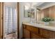 Bathroom with a white sink, cabinets, decorative mirror, and shower with patterned curtain at 6119 Zenobia Ct, Arvada, CO 80003