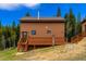 Exterior angle of home with wood siding, small deck with stairs, and mountain views at 33606 Gap Rd, Golden, CO 80403