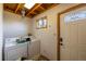 Functional laundry room with washer, dryer, exposed wood ceiling, and exterior door at 33606 Gap Rd, Golden, CO 80403