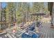 Relaxing deck with a fire pit, chairs, table, and an umbrella surrounded by tall trees at 32663 Donna Dr, Conifer, CO 80433