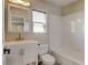 Bright bathroom featuring a white vanity, tub with white tile surround, and natural light from the window at 3769 Dahlia St, Denver, CO 80207