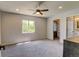 Spacious bedroom featuring soft gray carpet, a ceiling fan, and an ensuite bathroom and walk-in closet at 3769 Dahlia St, Denver, CO 80207