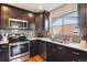 Close-up of updated kitchen featuring stainless steel appliances, dark wood cabinets and granite counters at 794 S Ivy St, Denver, CO 80224