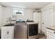 Well-lit laundry room featuring modern washer, dryer, sink, and storage cabinets for functionality at 794 S Ivy St, Denver, CO 80224
