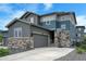Two-story home featuring gray siding and stone accents, a two-car garage, and a basketball hoop at 6950 Hidden Cove Ct, Castle Pines, CO 80108