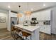 Bright kitchen featuring white cabinets, a large island, stainless steel appliances, and modern pendant lighting at 6950 Hidden Cove Ct, Castle Pines, CO 80108