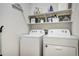 Functional laundry room with white appliances, patterned backsplash, and overhead shelving for organized storage at 6950 Hidden Cove Ct, Castle Pines, CO 80108