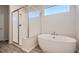 Bright bathroom featuring a walk-in shower with glass door and a freestanding soaking tub beneath a large window at 1300 Loraine N Cir, Lafayette, CO 80026