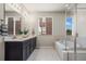 Modern bathroom with double vanity, soaking tub, and glass enclosed shower with tile flooring and natural light at 1677 Meagan Way, Erie, CO 80516