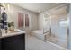 Modern bathroom with double vanity, soaking tub, and glass enclosed shower with tile flooring and bright light at 1677 Meagan Way, Erie, CO 80516