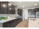 Modern kitchen features a large island, gas range, and dark cabinets at 1677 Meagan Way, Erie, CO 80516