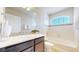Well-lit bathroom features a modern vanity with sleek countertops, a tiled backsplash, and a pristine tub with shower combination at 172 Painted Horse Way, Erie, CO 80516