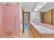Bathroom showcasing pink tiling, shower and tub, wooden vanity, bright lighting, and decorative mirrors at 2501 E Arkansas Ave, Denver, CO 80210