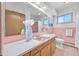 Bathroom featuring light pink tiling, wooden vanity, white countertops, and decorative mirrors at 2501 E Arkansas Ave, Denver, CO 80210