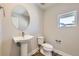 Elegant powder room featuring pedestal sink, oval mirror, and modern fixtures at 858 Promenade Dr, Superior, CO 80027