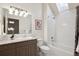 Bright bathroom featuring granite countertop, vanity, shower-over-tub with white tile surround, and skylight at 50 S Eudora St, Denver, CO 80246