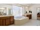 Well-lit bathroom featuring a soaking tub under a window, vanity sinks, and a private toilet area for added convenience at 1021 Neptunite Pl, Castle Rock, CO 80108