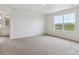Carpeted bedroom featuring neutral walls, a window with a view, and adjacent bathroom access at 27574 E Byers Ave, Aurora, CO 80018